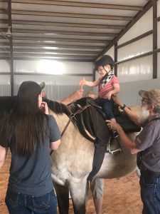 a boy on a horse surrounded by therapists